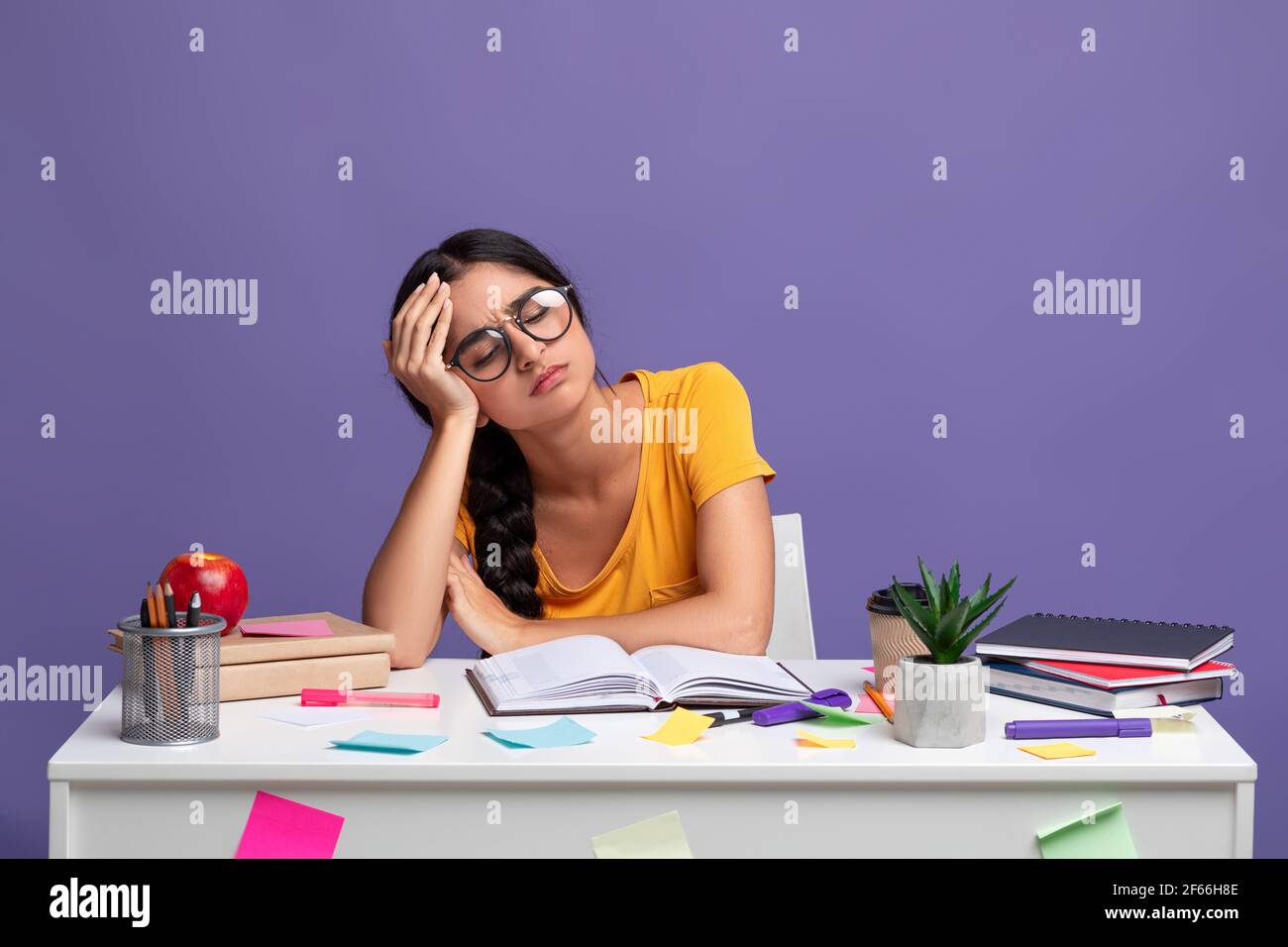 Tired indian woman in glasses sitting at desk reading book Stock Photo ...