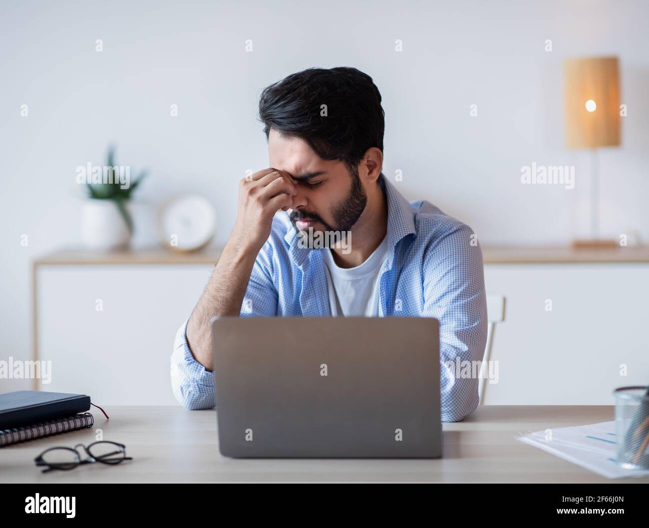 Desperate Eastern Freelancer Sitting At Desk With Laptop, Suffering Lack Of Inspiration Stock Photo