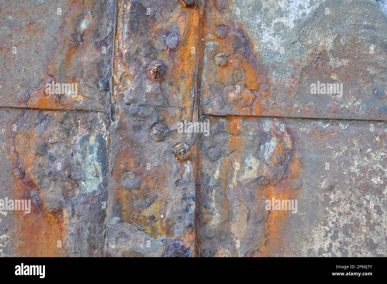 Rusty ships plates, now used to reinforce the river bank.Bright coloured in the sun.Hayle. Cornwall. UK. Stock Photo