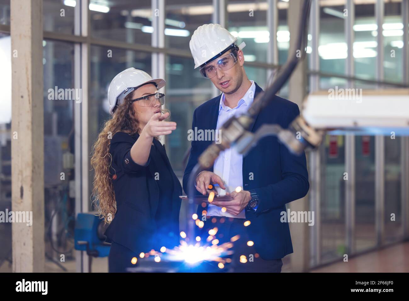 Engineer supervising autonomous producton process industry robot arm in ...