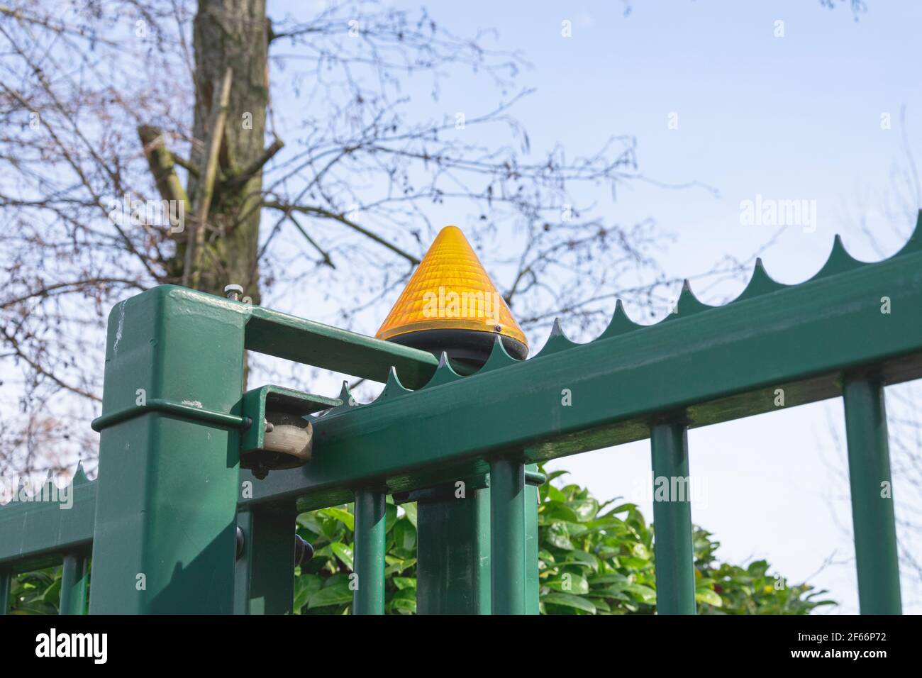 Orange lamp on an automatic green gate that activates when the gate opens Stock Photo