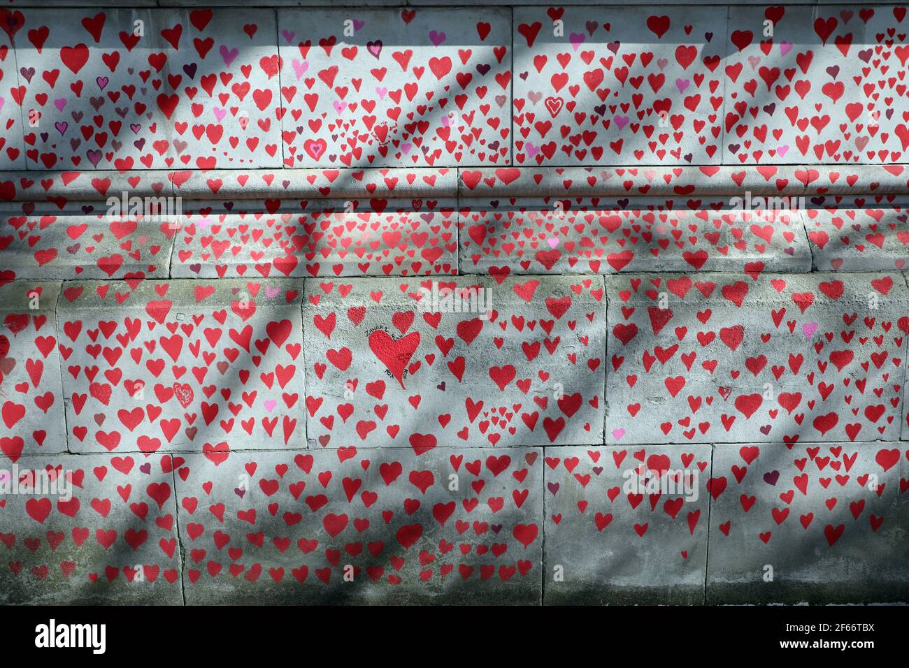 London, UK. 30th Mar, 2021. Hearts of the National Covid Memorial drawn by the Bereaved Friends and Family of Covid-19 on the embankment of the River Thames opposite the Houses of Parliament. The first of around 150,000 hearts which will be drawn on several hundred metres of the wall outside St. Thomas' Hospital in London, where Boris Johnson was admitted on contracting Covid last year. Credit: Paul Brown/Alamy Live News Stock Photo
