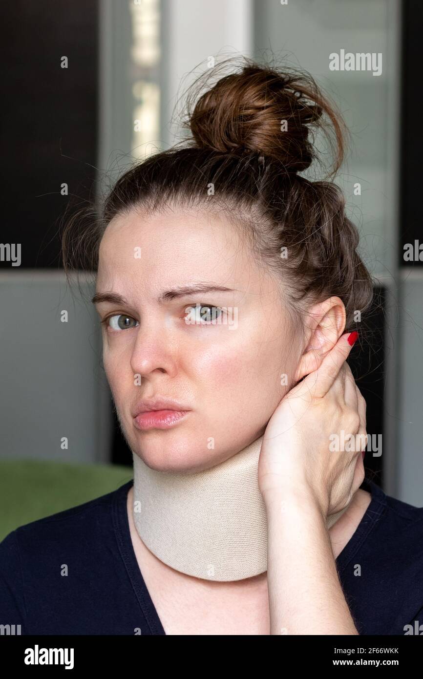 Unhappy woman with cervical surgical collar feeling pain in neck. Vertical photo. Stock Photo