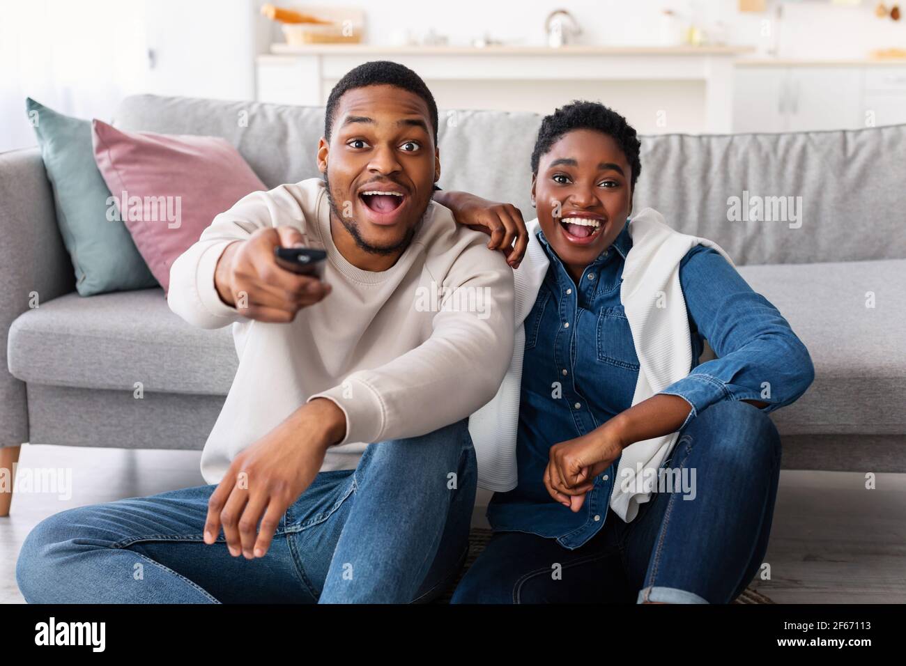 Excited black couple spending weekend together watching tv Stock Photo