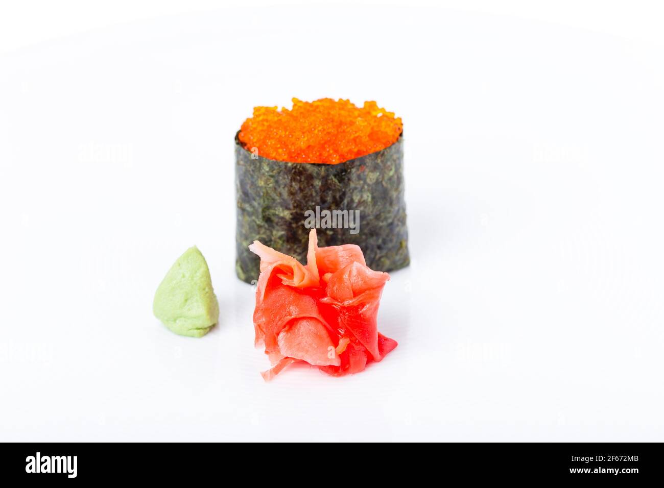 Gunkan sushi stuffed with red tobiko caviar. Served with heap of ginger and wasabi. Selective focus on heap of ginger. Macro. Can be used as a whole b Stock Photo