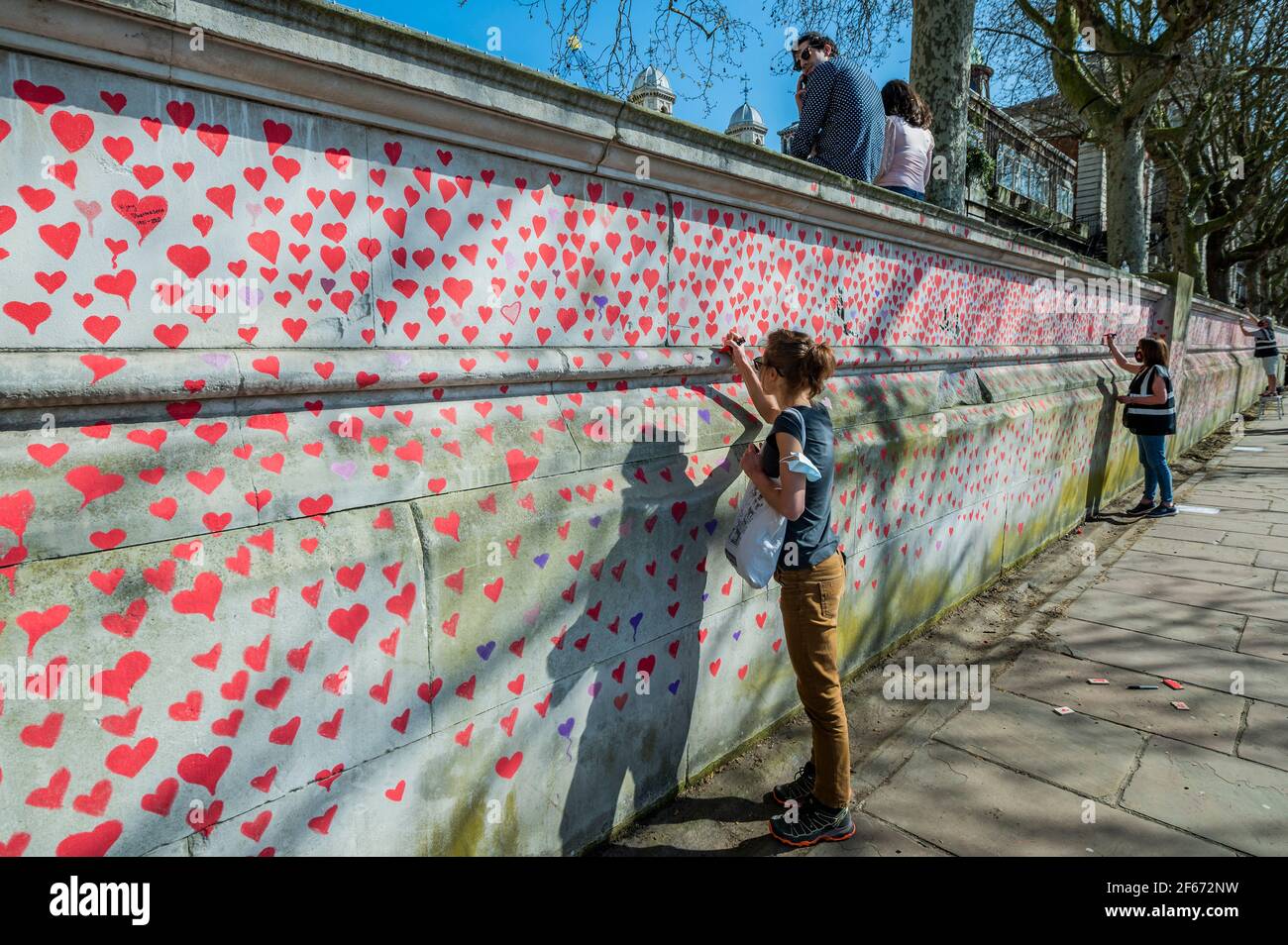 London, UK. 30 Mar 2021. The national Covid Memorial Wall outside St Thomas' Hospital on the southbank. Family and friends of some of the more than one hundred and forty-five thousand people who've lost their lives to Covid-19 are drawing hearts by hand on a wall opposite Parliament in London. Each heart represents someone who was loved. Someone who was lost too soon to Covid-19. They are organising this temporary memorial themrselves because 'they do not believe it is for those who led this country's response to Covid-19 to decide how we grieve'. Once installed they will keep the memorial up Stock Photo