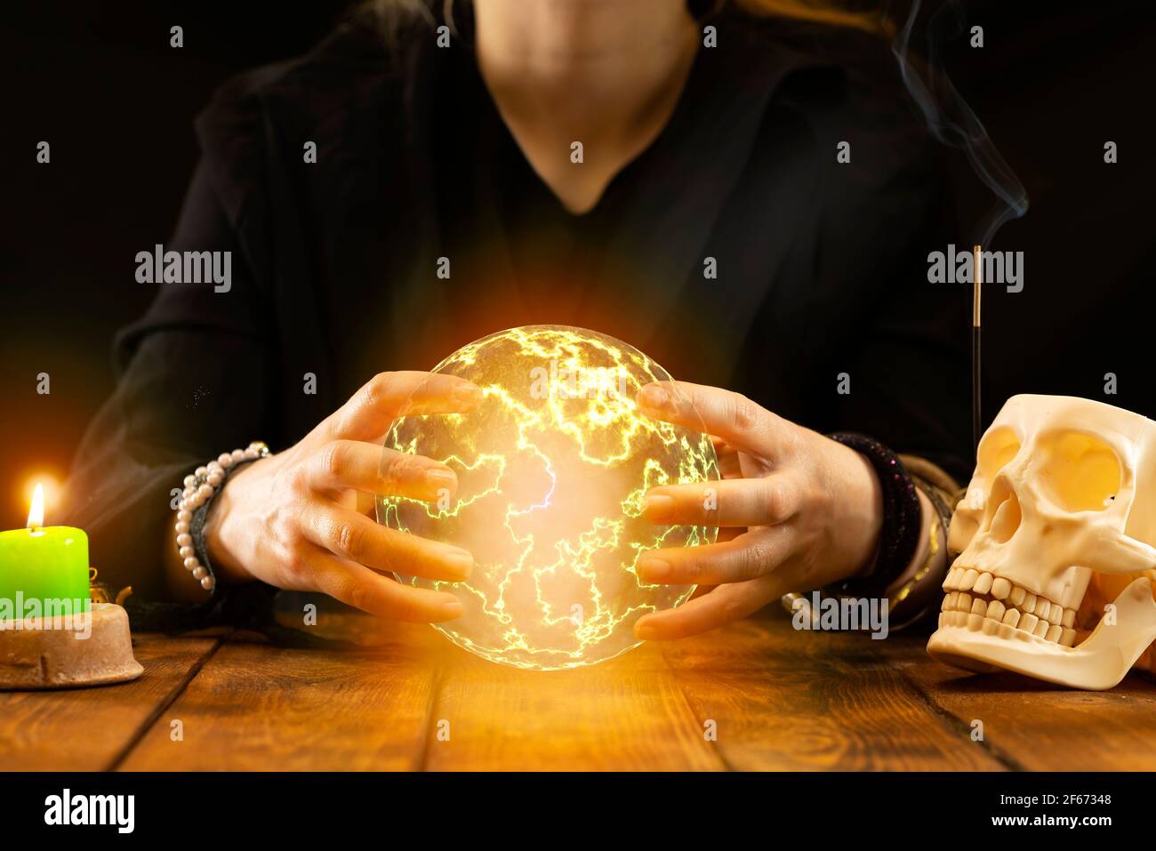 A fortune-teller or oracle with objects for fortune-telling holds a fireball in his hands to predict the future during the session. Psychic readings a Stock Photo