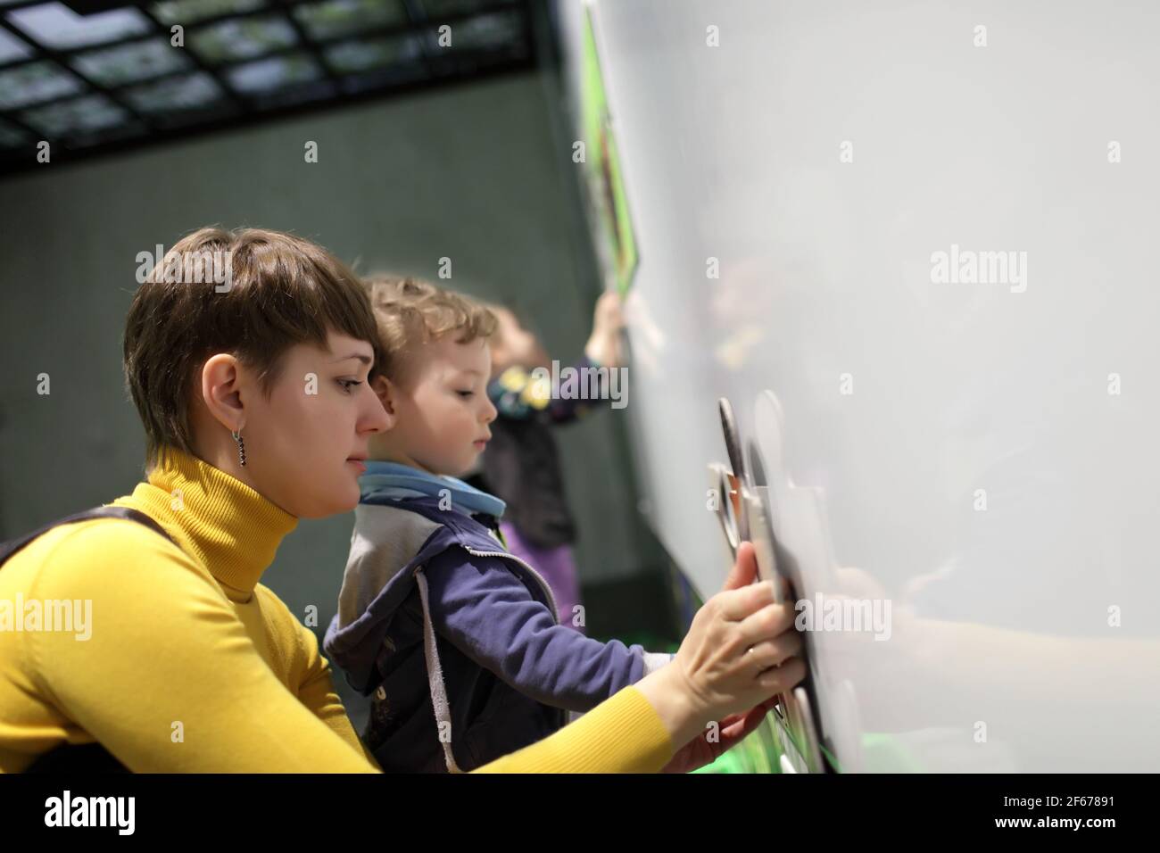 Mother and her son solving puzzles in a playroom Stock Photo