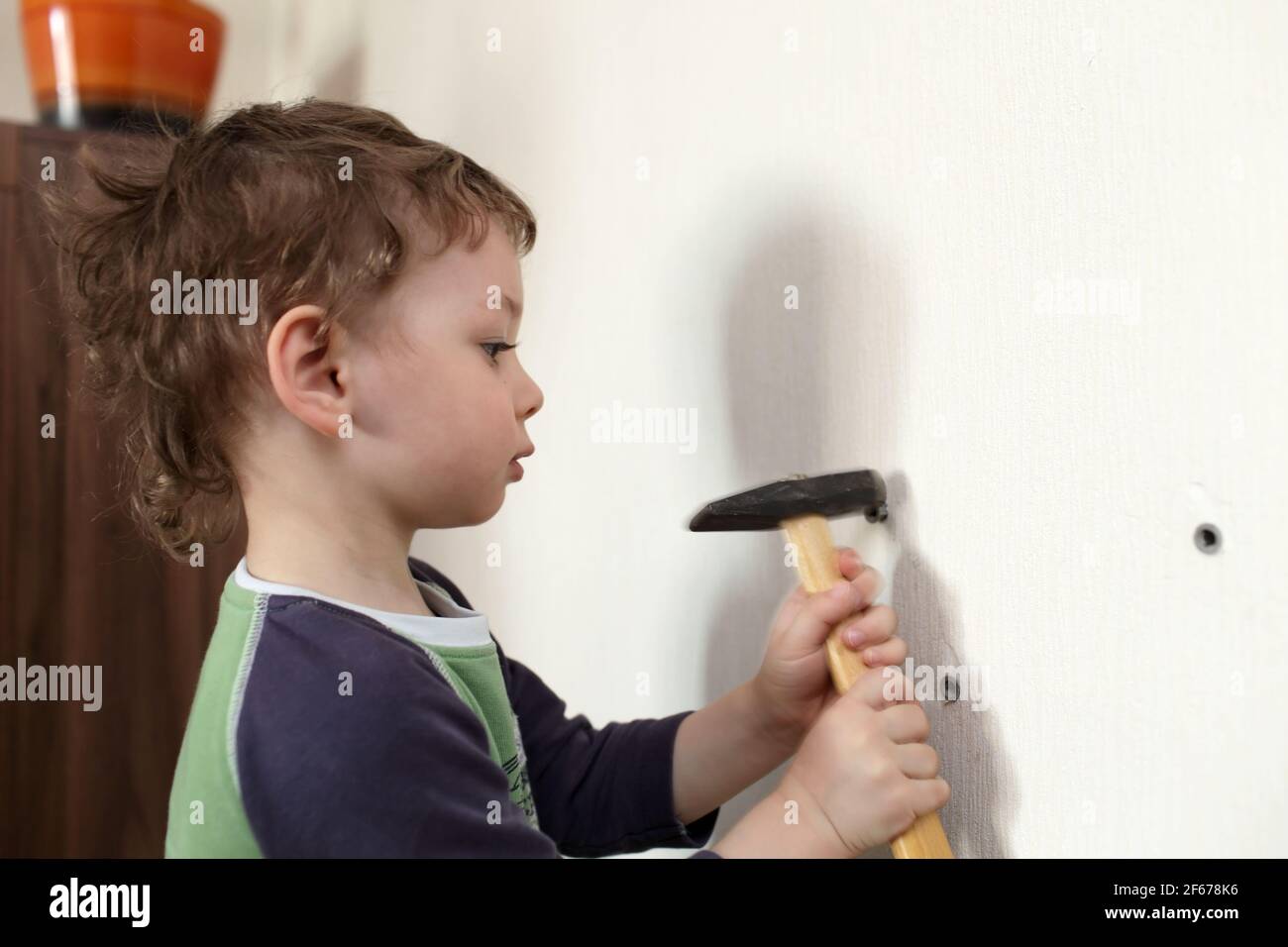 Kid hammering plastic anchor into wall at home Stock Photo - Alamy