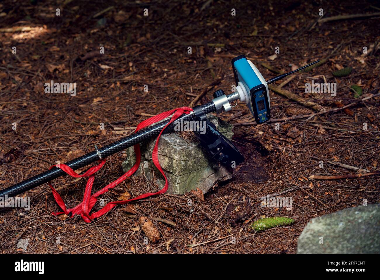 GPS on a rod with hand keyboard on the ground in forest. Land Surveying equipment Stock Photo