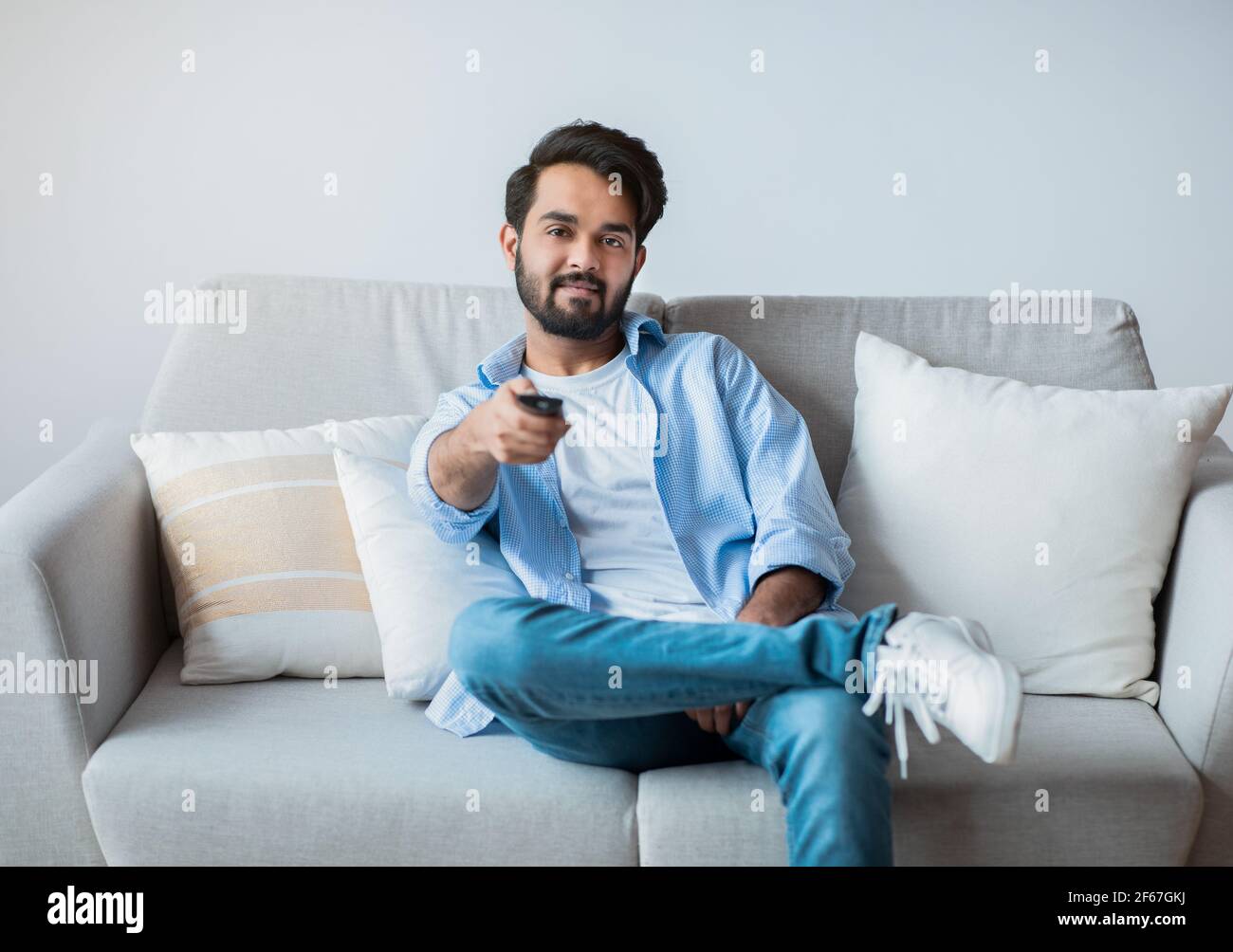 Smiling Young Middle Eastern Guy Watching TV At Home. Stock Photo