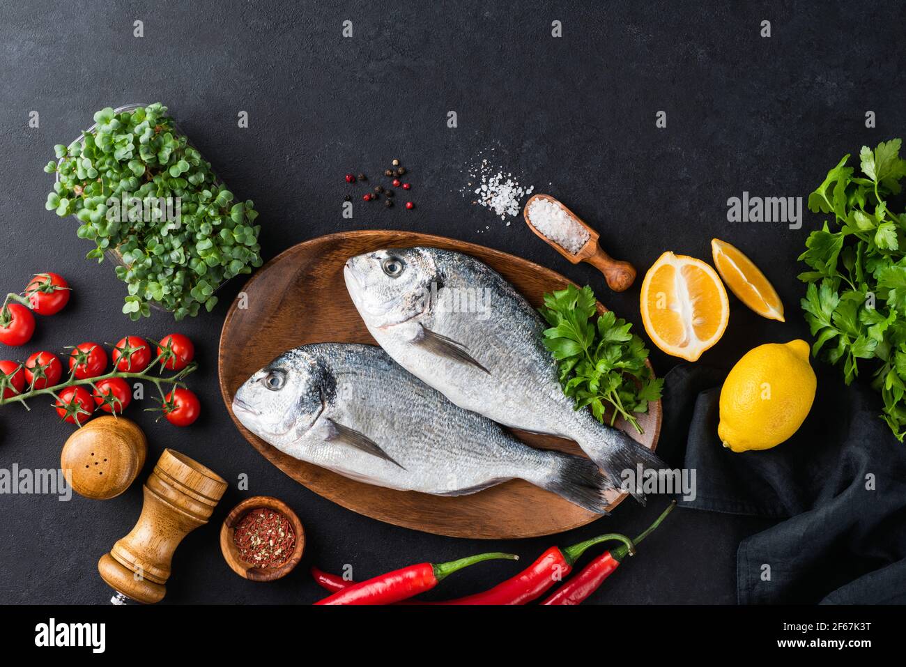 Two fresh dorado fish and ingredients for cooking on black slate  background, top view with copy space for text or design elements. Uncooked  raw fish Stock Photo - Alamy