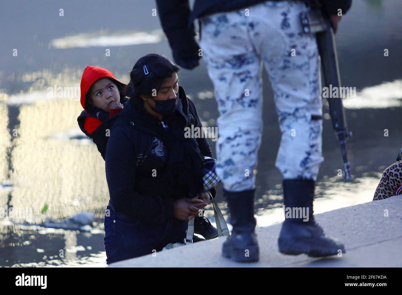 A migrant boy looks to a member of the Guardia Nacional (National guard)  before crossing with his mother the Rio Bravo river to turn themselves into U.S Border Patrol agents to request asylum in El Paso, Texas, U.S., as seen from Ciudad Juarez, Mexico, March 30, 2021. REUTERS/Edgard Garrido Stock Photo