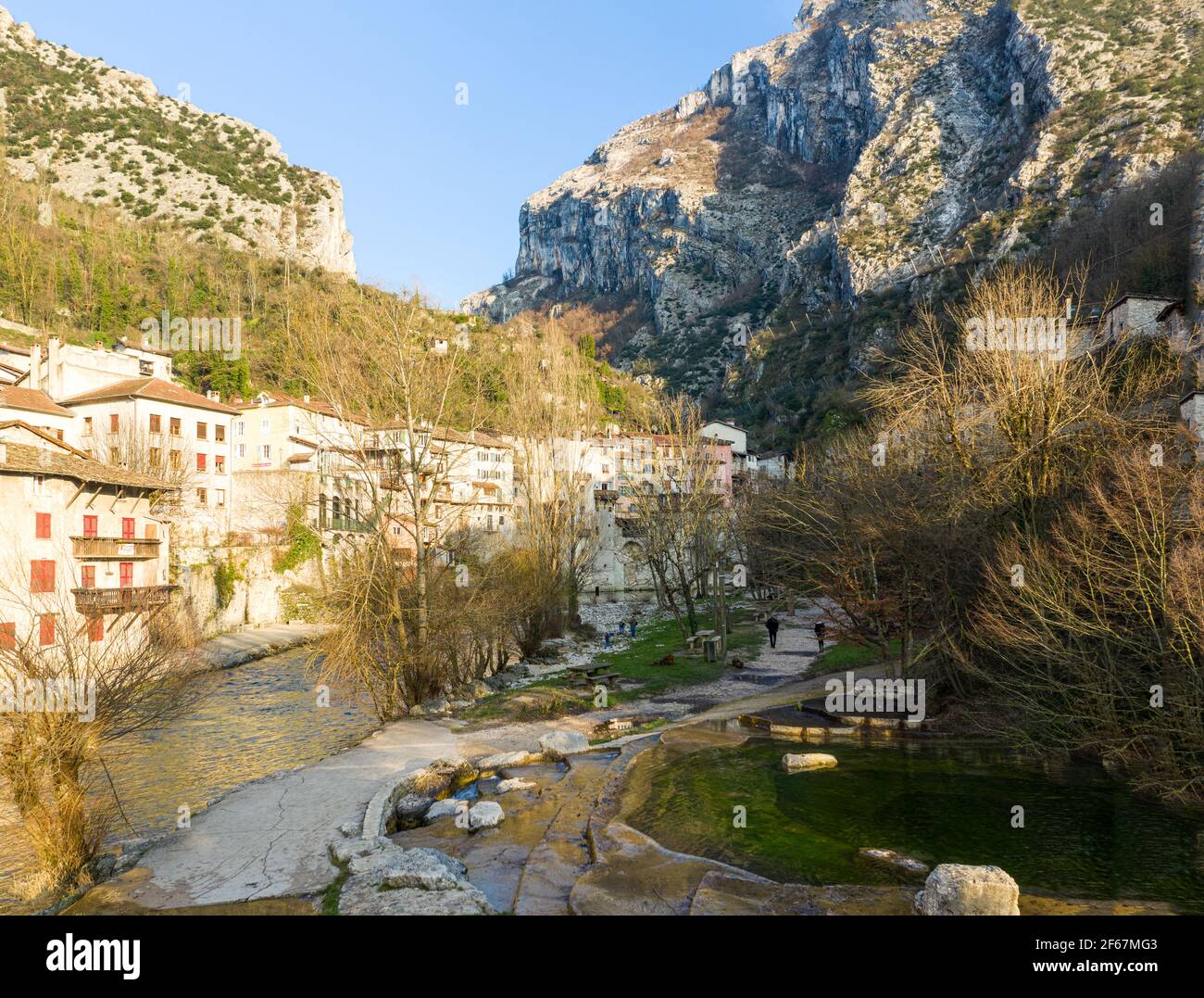Buildings in village under steep limestone rock walls of Vercors mountains, France. Morning sunshine. Stock Photo