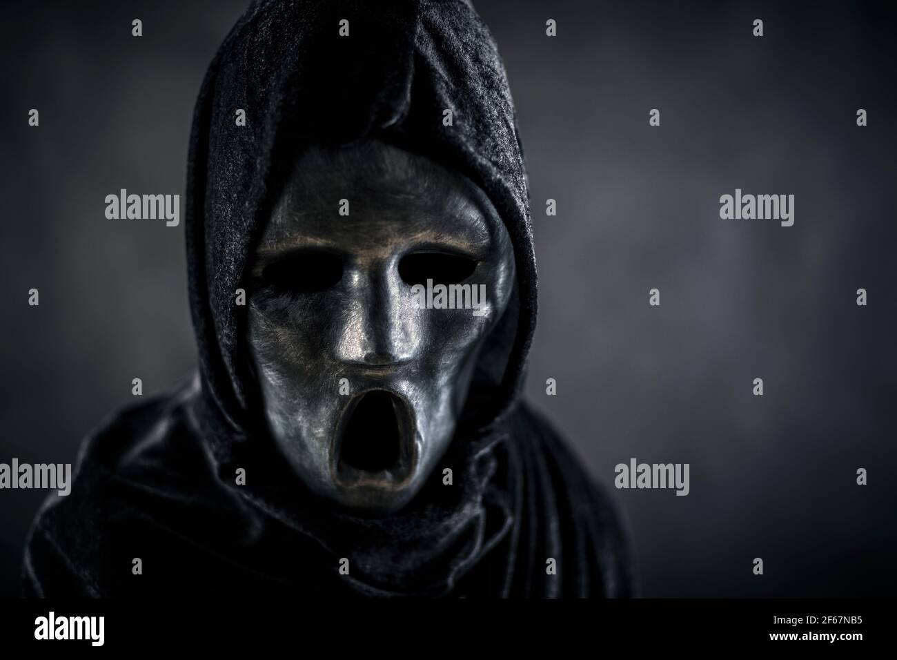 Scary figure with hooded cape in the dark Stock Photo - Alamy