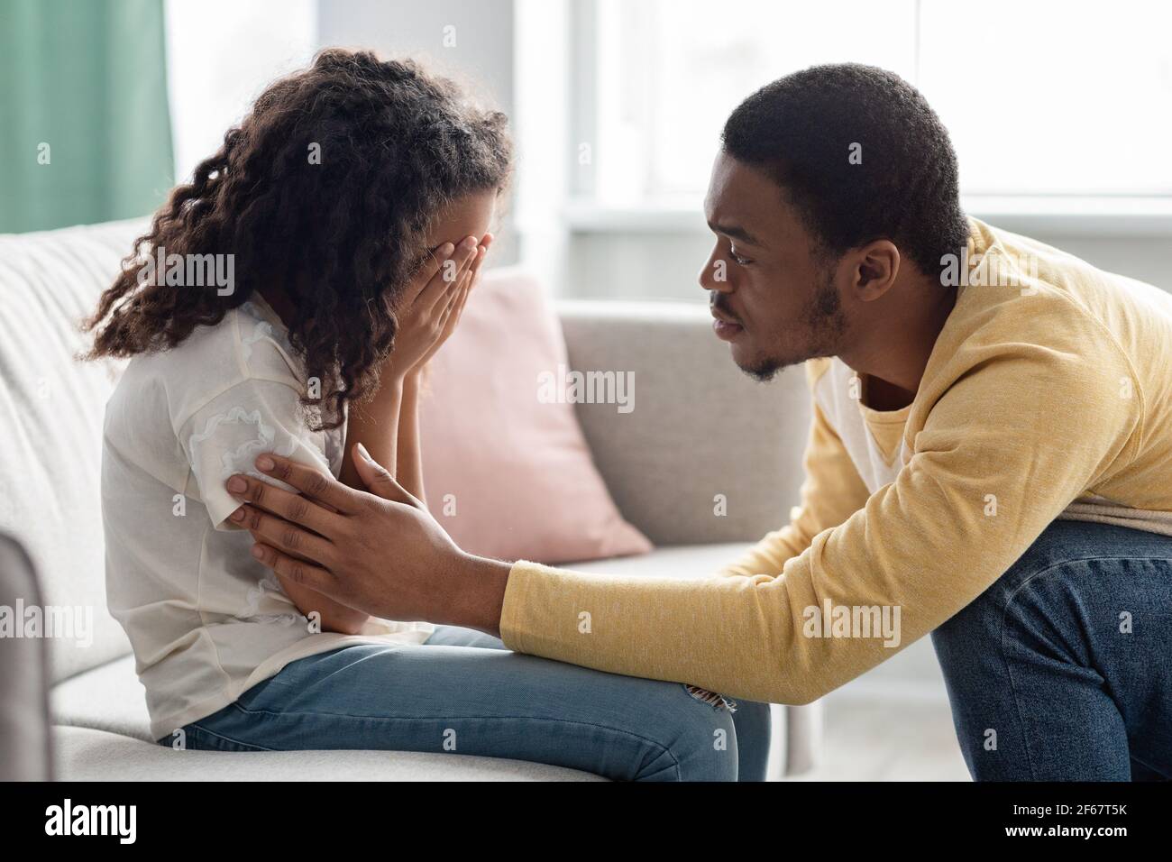 Black father comforting his crying kid, home interior Stock Photo