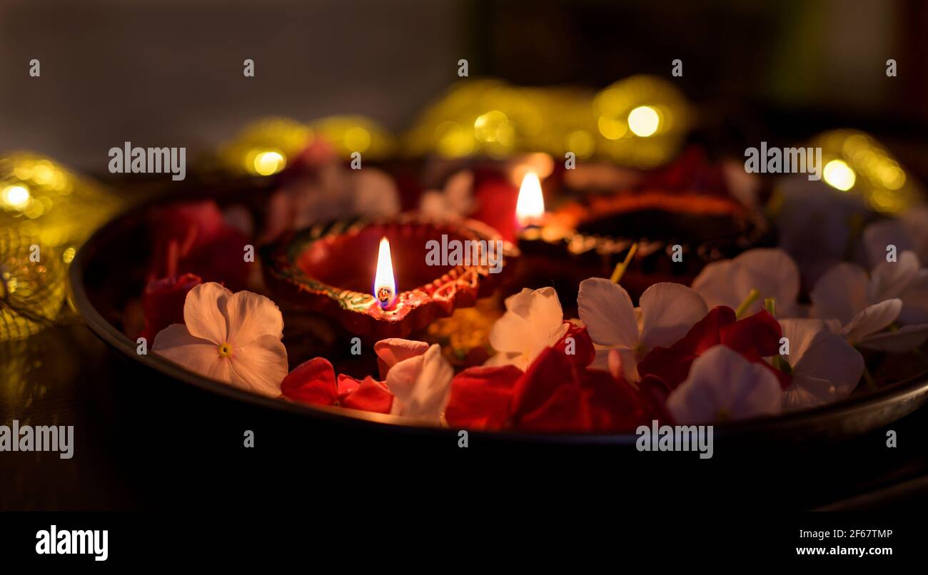 Colorful Diwali oil lamps lighted in beautiful formation with flowers,serial lights in a bokeh at the background during the hindu festival deepavali. Stock Photo