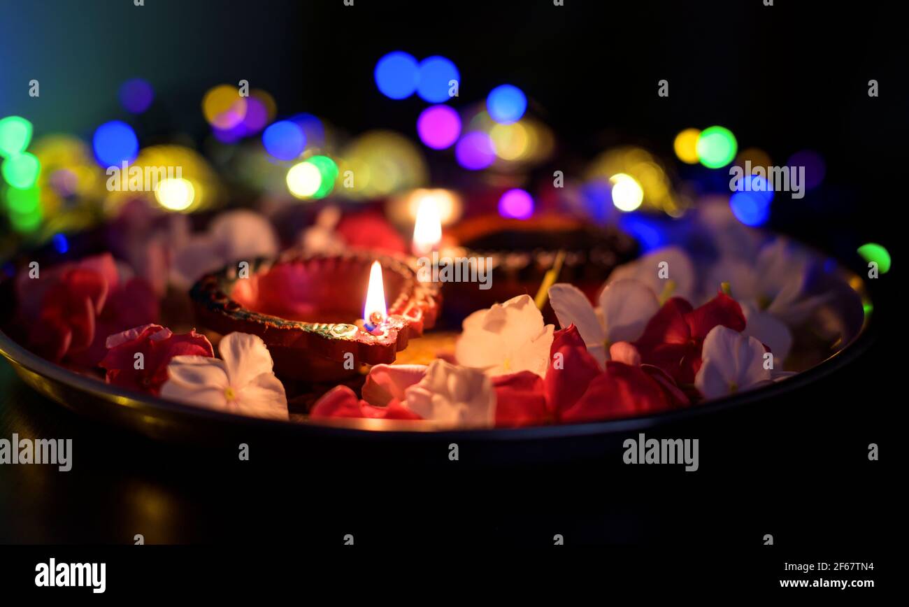 Colorful Diwali oil lamps lighted in beautiful formation with flowers,serial lights in a bokeh at the background during the hindu festival deepavali. Stock Photo