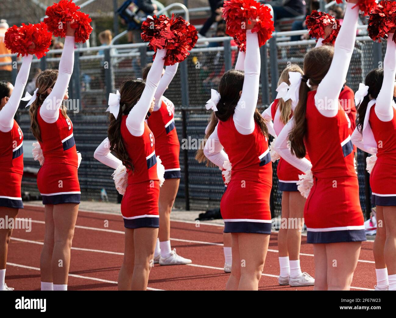 High school cheerleaders cheering to the fans in the bleachers during a football game. Stock Photo