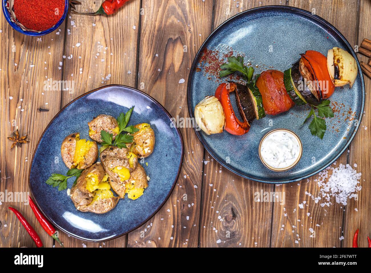 Boiled potatoes, coarse salt, grilled vegetables on a brown wooden background. Copy the space. Stock Photo