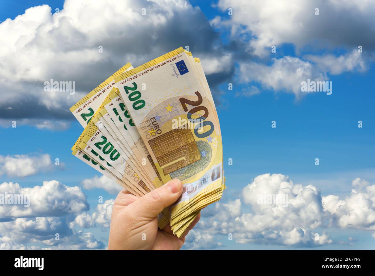 Frauenhand hält Zwei-Hundert -Euroscheine in den Himmel. Stock Photo