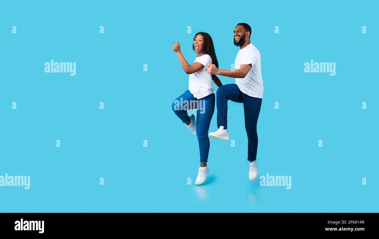 Happy young black couple walking and jumping at studio Stock Photo