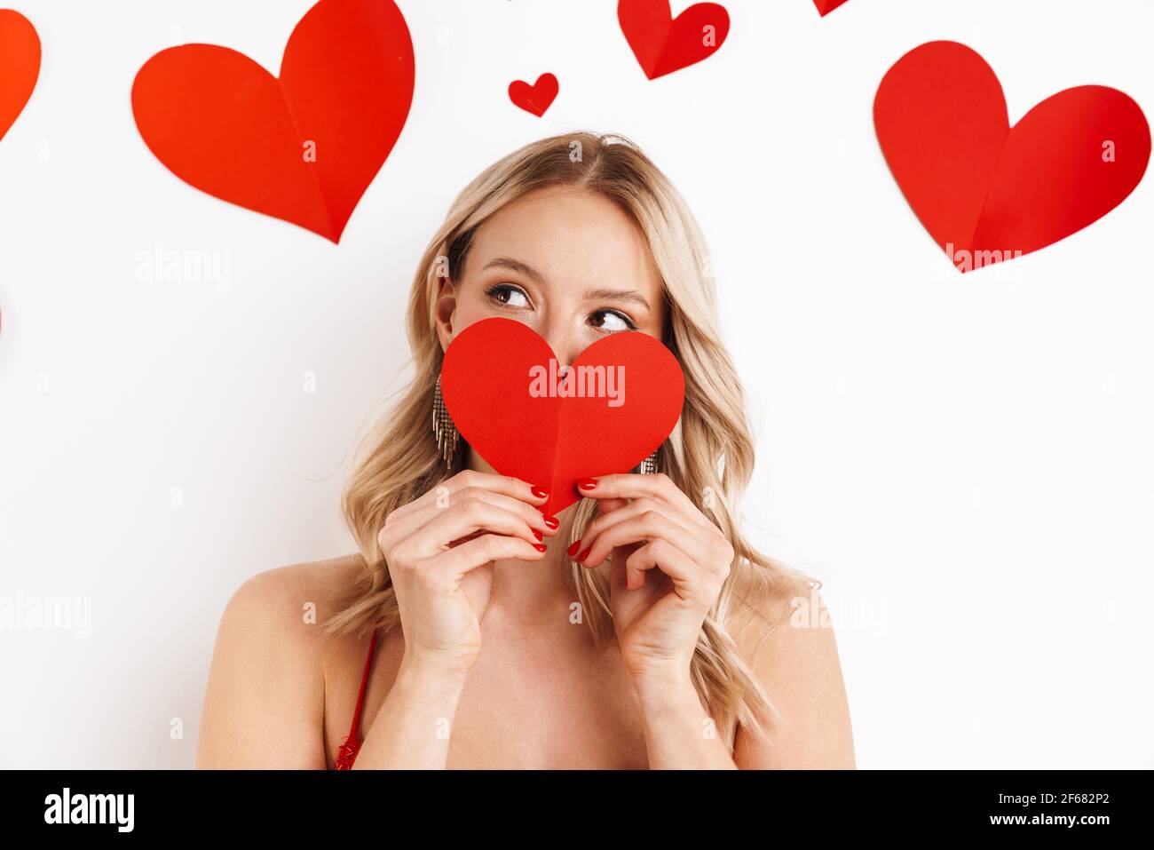 Happy beautiful girl in red dress posing with paper heart isolated over ...