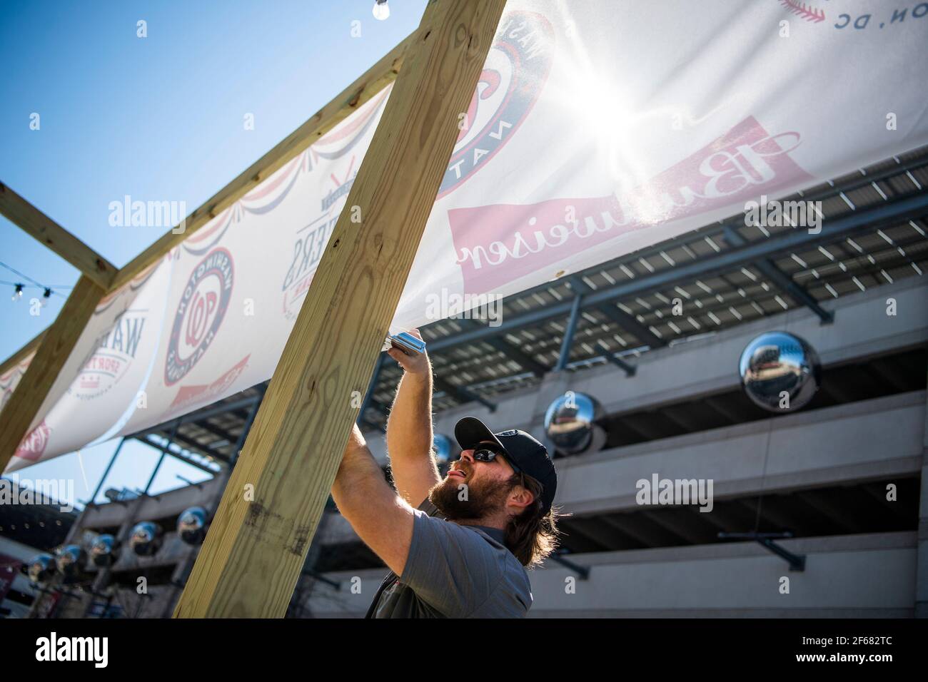 UNITED STATES - MARCH 30: An employee of Capital Eagle Inc. installs banners on the patio of Walters Sports Bar ahead of Major League Baseball Opening Day on Tuesday, March 30, 2021. Nationals Park, in the background, conducted a media tour to explain the health and safety protocols implemented due to the ongoing coronavirus pandemic. (Photo By Tom Williams/CQ Roll Call/Sipa USA) Stock Photo