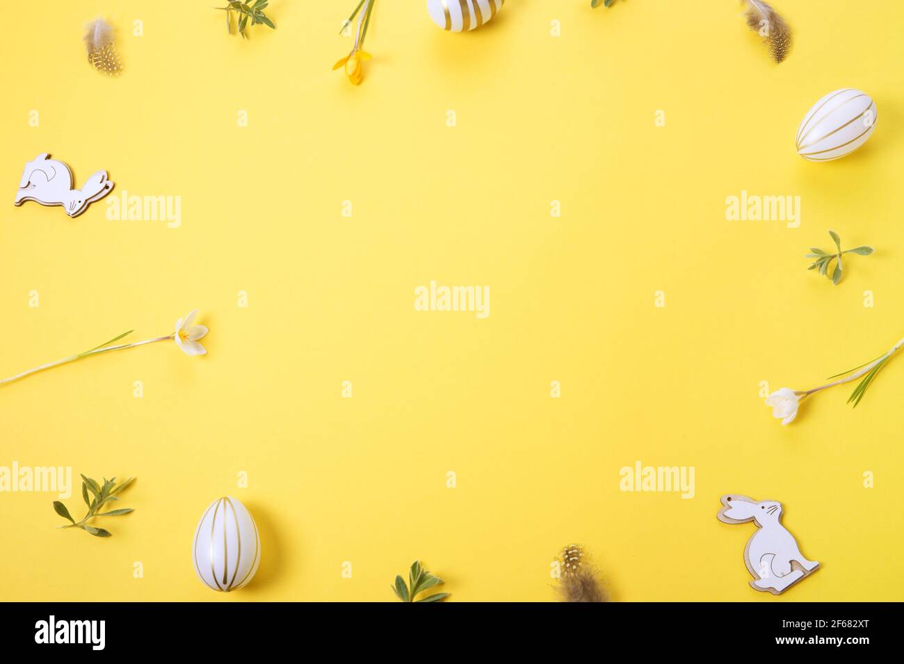 Festive Easter border, frame from easter eggs and spring flower crocus on yellow background. Stylish easter flat lay yellow Stock Photo