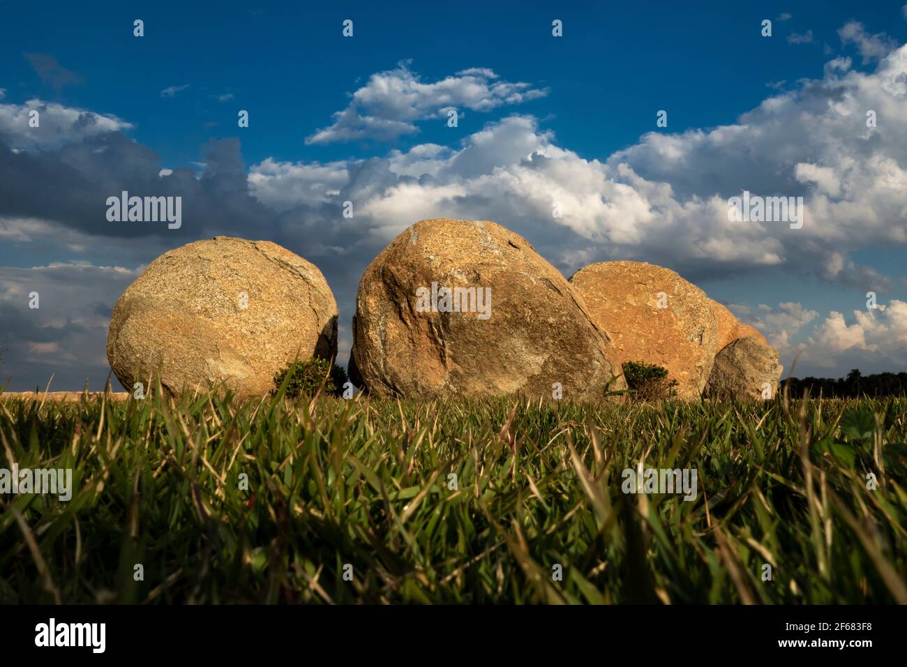 A trinity of rocks on a grass field Stock Photo