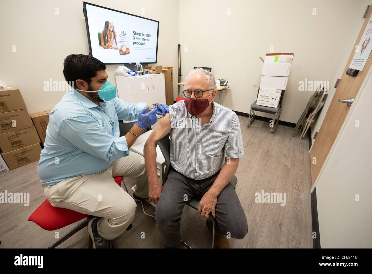 Austin, Texas March 30, 2021:  BOB DAEMMRICH (r), 66, gets his second shot of Pfizer's coronavirus vaccine at a local pharmacy, three weeks after the first in the same location. Texas is reporting larger shipments of vaccinations and 1 in 6 eligible Texans are fully vaccinated, around 16%. Stock Photo