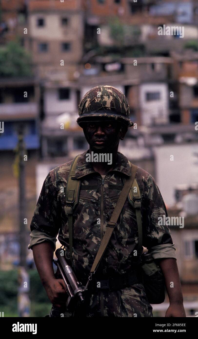 Military person combating urban violence at Rio de Janeiro favela. Army occupation of deprived areas as part of the Government policy of public security in preparation for the 2014 FIFA World Cup in Brazil. Stock Photo