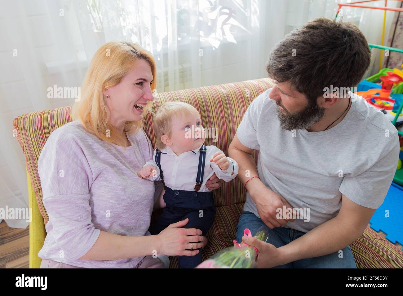 Dad with children congratulate mom on the holiday, mother's day. Have fun, laugh and give flowers Stock Photo