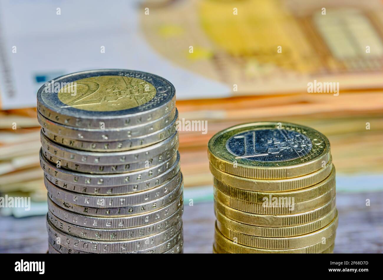 stack of one and two Euro coins in front of European banknotes, blurred ...