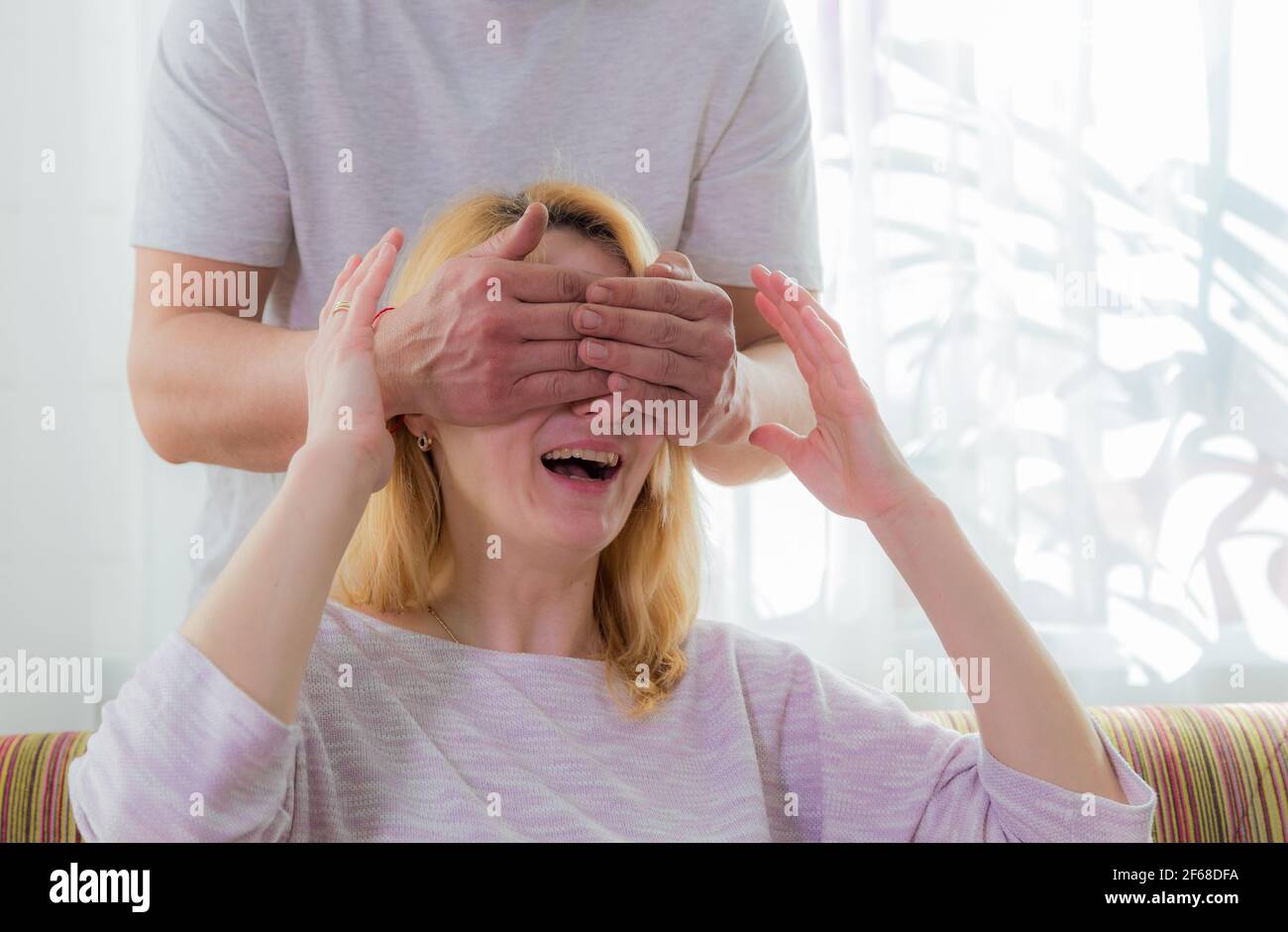 The family makes a surprise for mom, wishes her a happy holiday. Dad covered his mother's eyes with his palms. Stock Photo