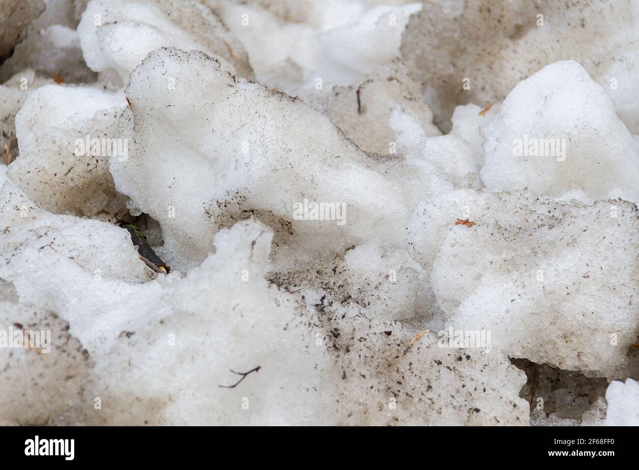 Early spring time dirty gray melted snow with sand pattern texture close-up Grunge background Stock Photo