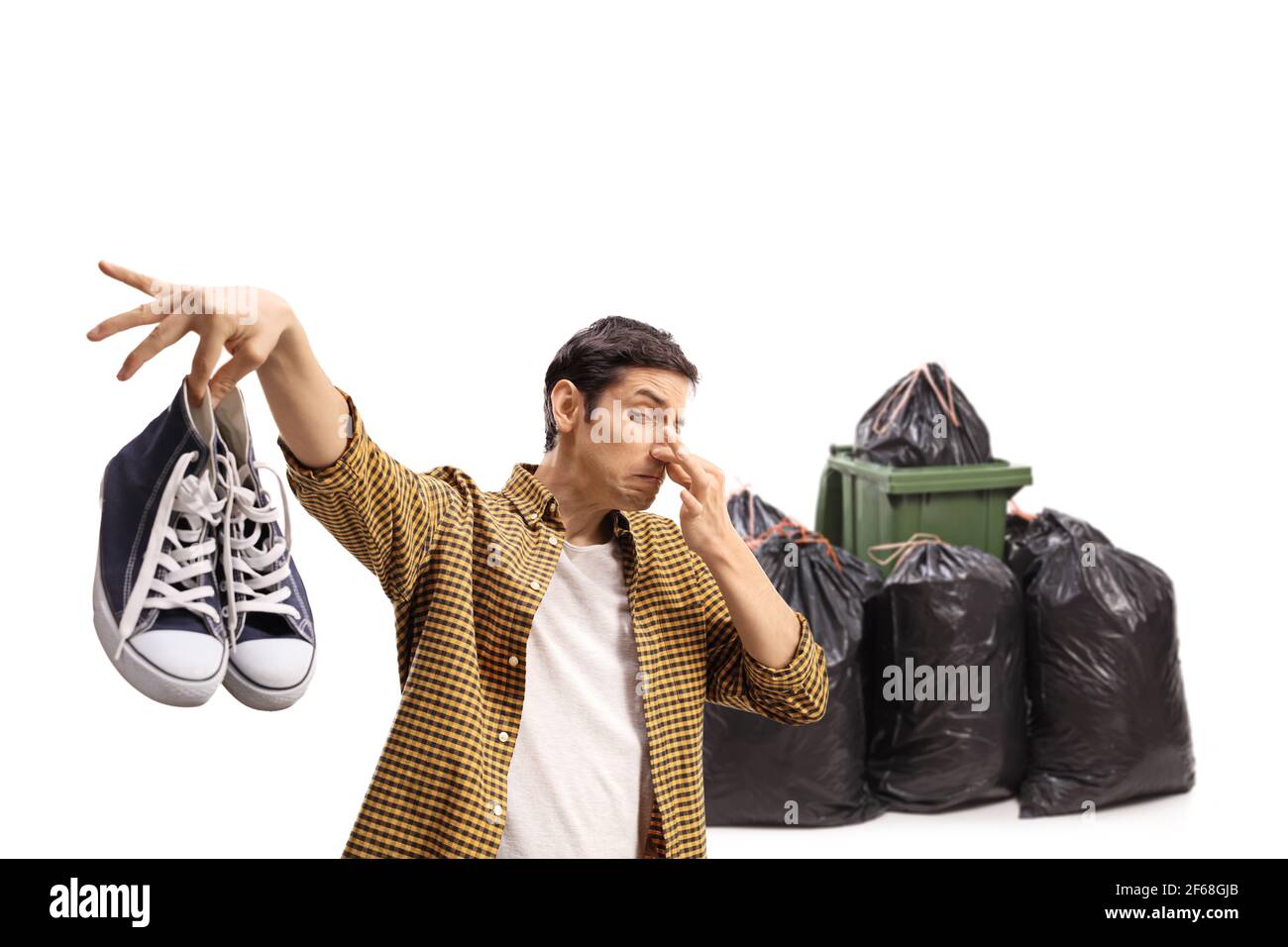 Guy throwing a pair of smelly trainers in garbage isolated on white background Stock Photo