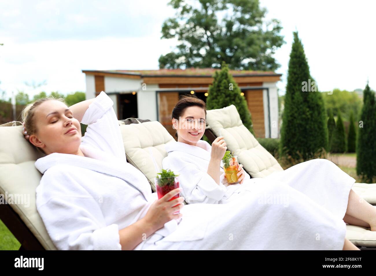 Couple are sunbathing on the sun loungers. Women relax in a luxurious spa. Two women are relaxing on sun loungers on a sunny summer day Stock Photo