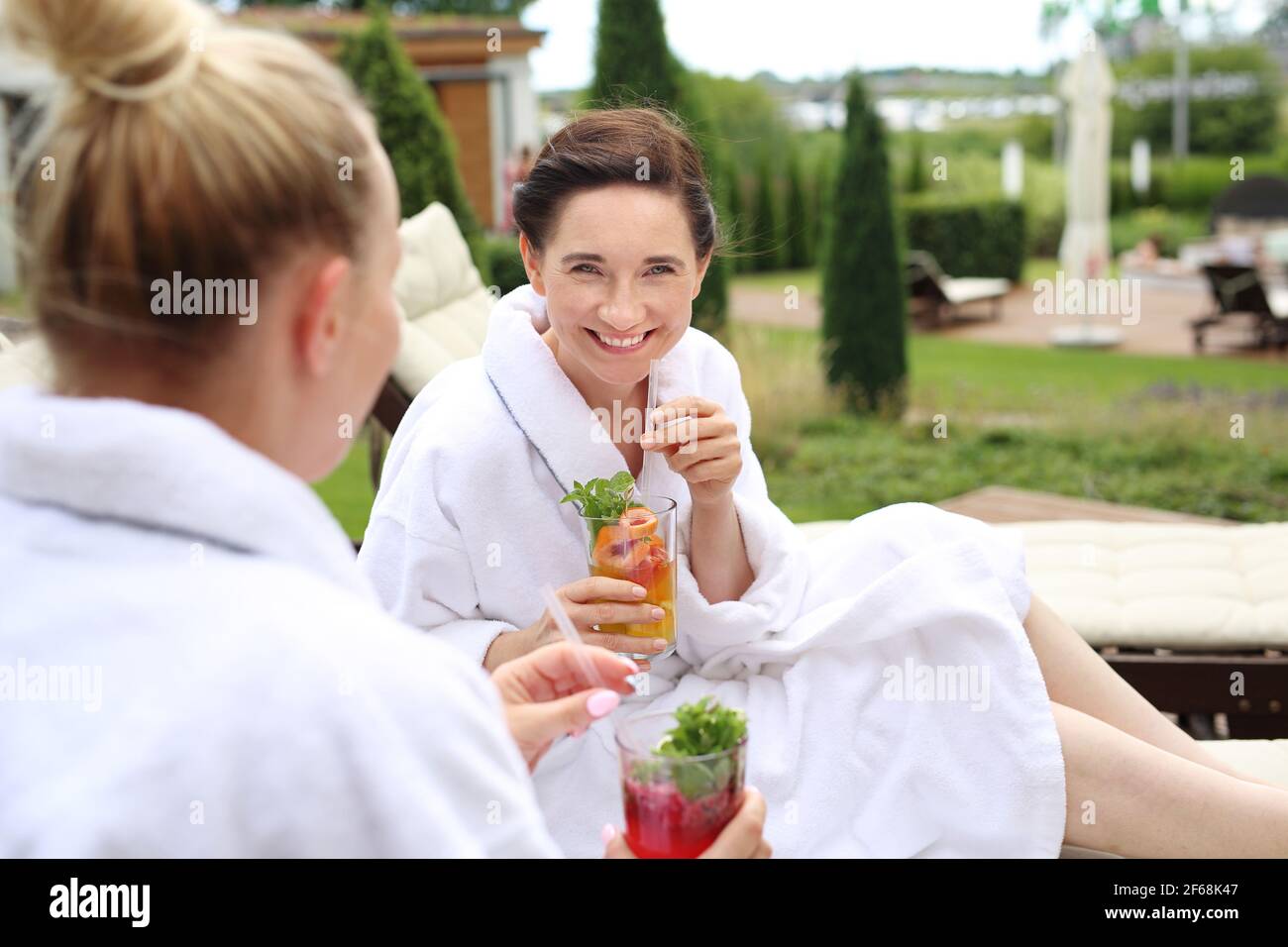 Couple are sunbathing on the sun loungers. Women relax in a luxurious spa. Two women are relaxing on sun loungers on a sunny summer day Stock Photo