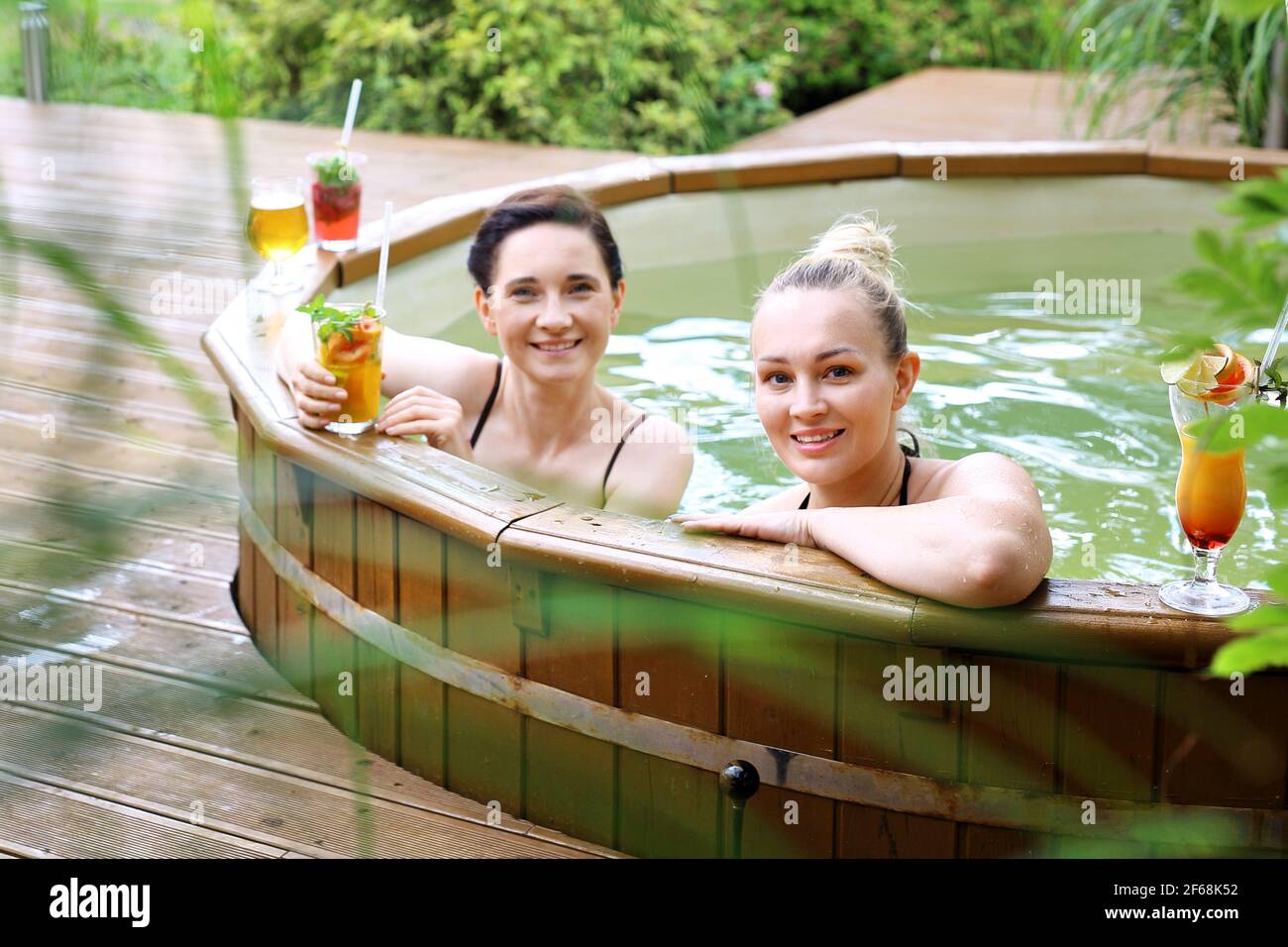 Bathing in a spa tub. Two beautiful women enjoy a relaxing bath in the tub. Girl friends at the spa. Stock Photo