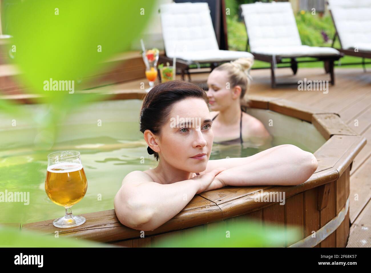 Bathing in a spa tub. Two beautiful women enjoy a relaxing bath in the tub. Girl friends at the spa. Stock Photo