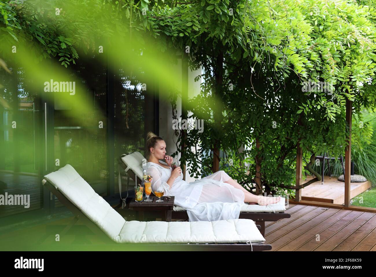 Woman relaxing at the spa. Relax in the garden. Young woman relaxes sitting on a hammock in the green garden. Stock Photo
