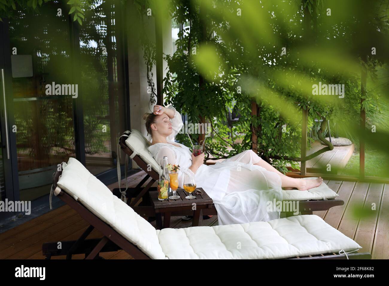 Woman relaxing at the spa. Relax in the garden. Young woman relaxes sitting on a hammock in the green garden. Stock Photo