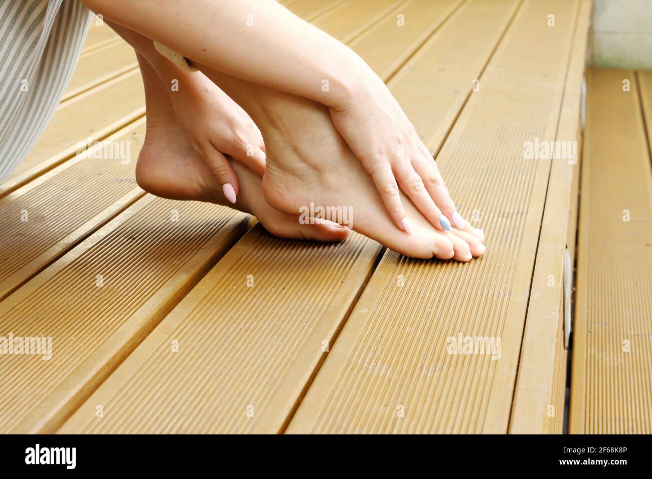 Bare feet. A woman is standing barefoot on the wooden floor. Stock Photo