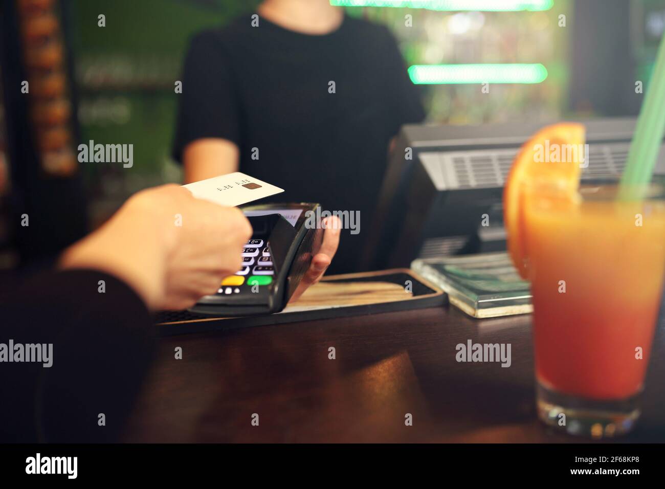 Payment by card. The woman pays the bill at the bar with a payment card. Stock Photo