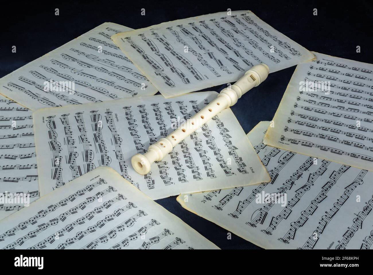 white fipple soprano flute recorder lies on sheet music scores Stock