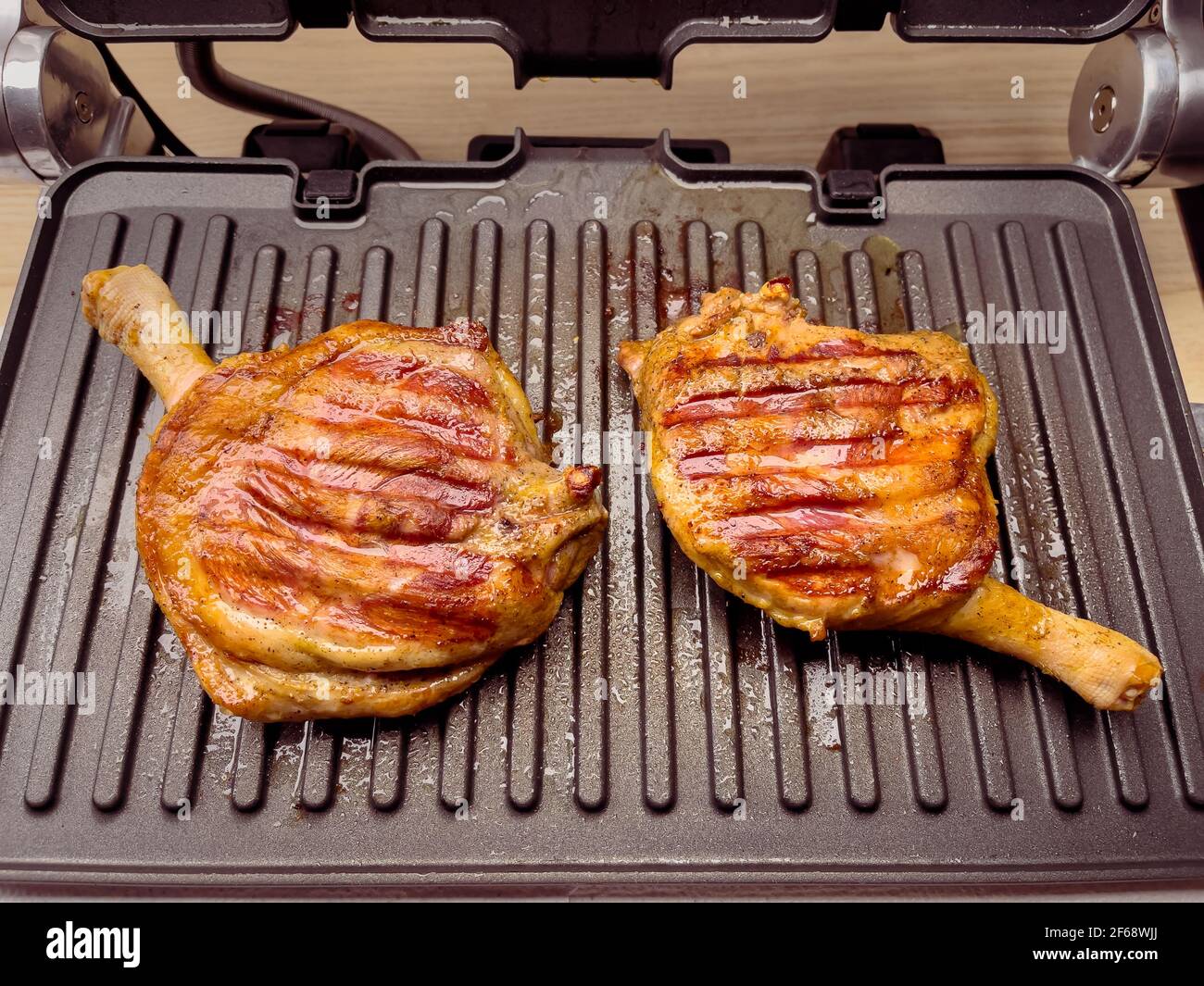 Homemade grilled duck thighs. Preparing duck meat on electric grill