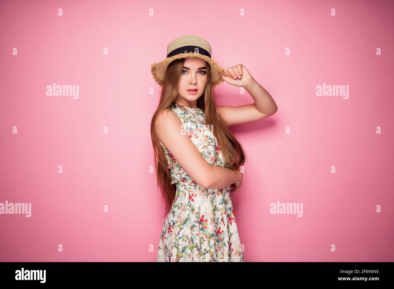 Winsome girl in romantic dress with flower print and straw hat p Stock Photo