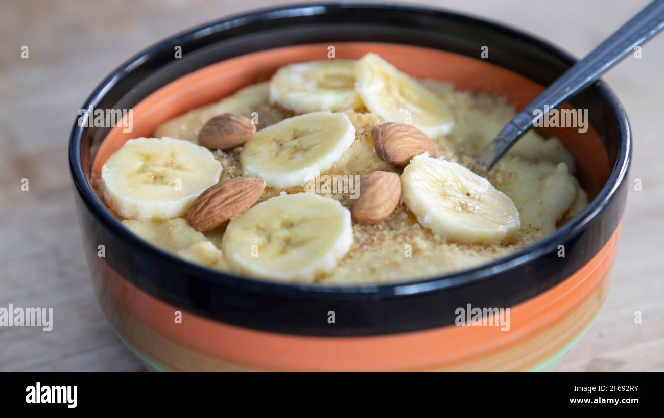 Almonds and banana with in a bowl of cornmeal porridge Stock Photo