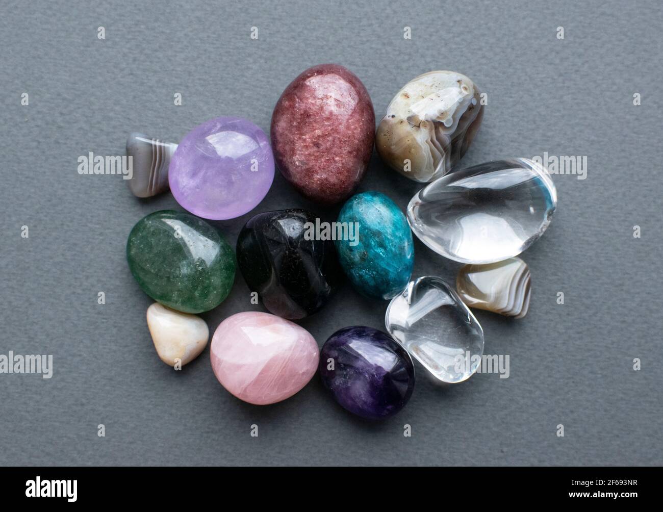 Tumbled gems of various colors. Amethyst, rose quartz, agate, apatite, aventurine, olivine, turquoise,  rock crystal. Stock Photo